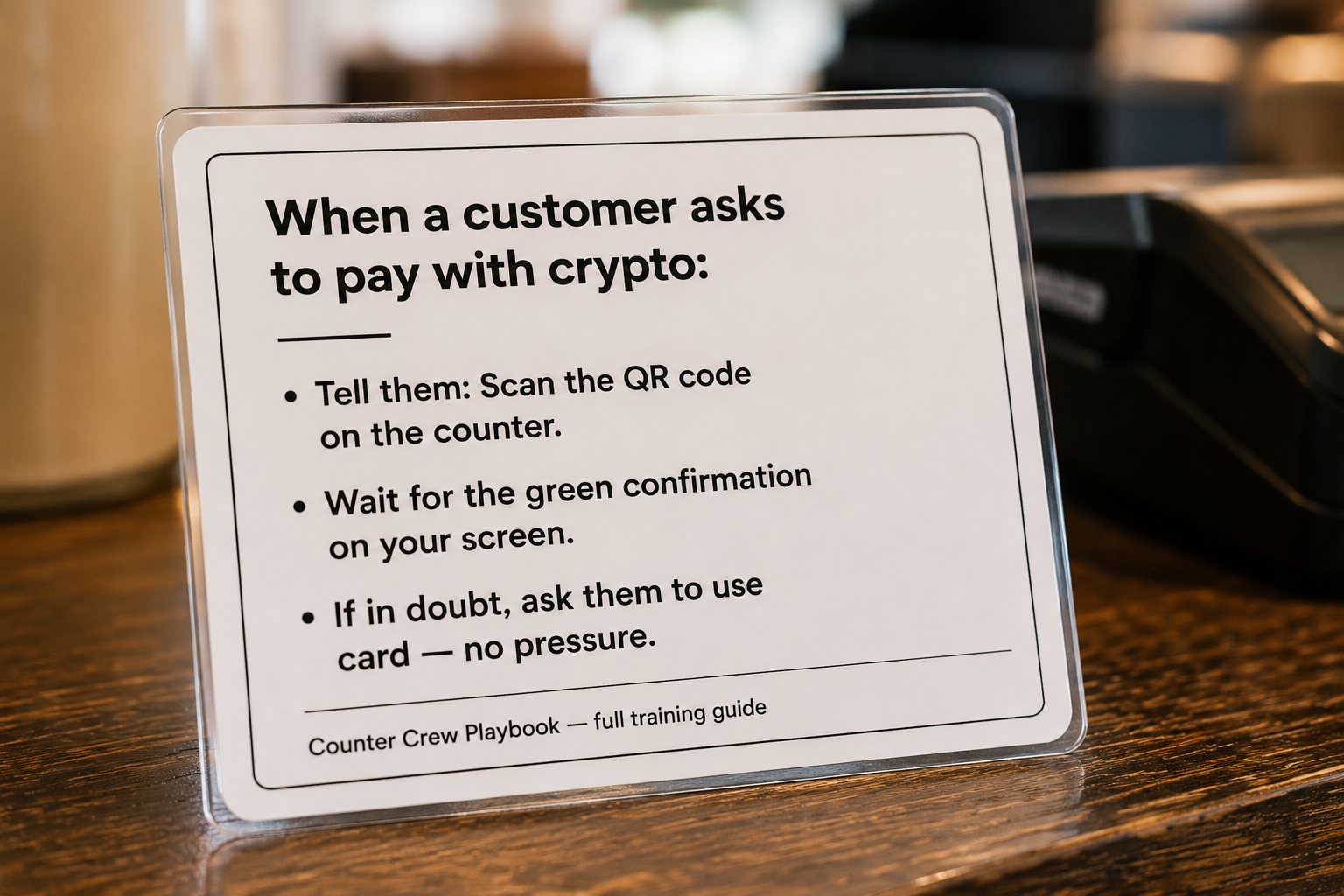 Laminated staff checkout script card on a counter with three bullet points explaining how to handle a crypto payment
